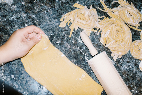 pov lo-fi ugc of hand hand rolling and cutting pasta noodles photo