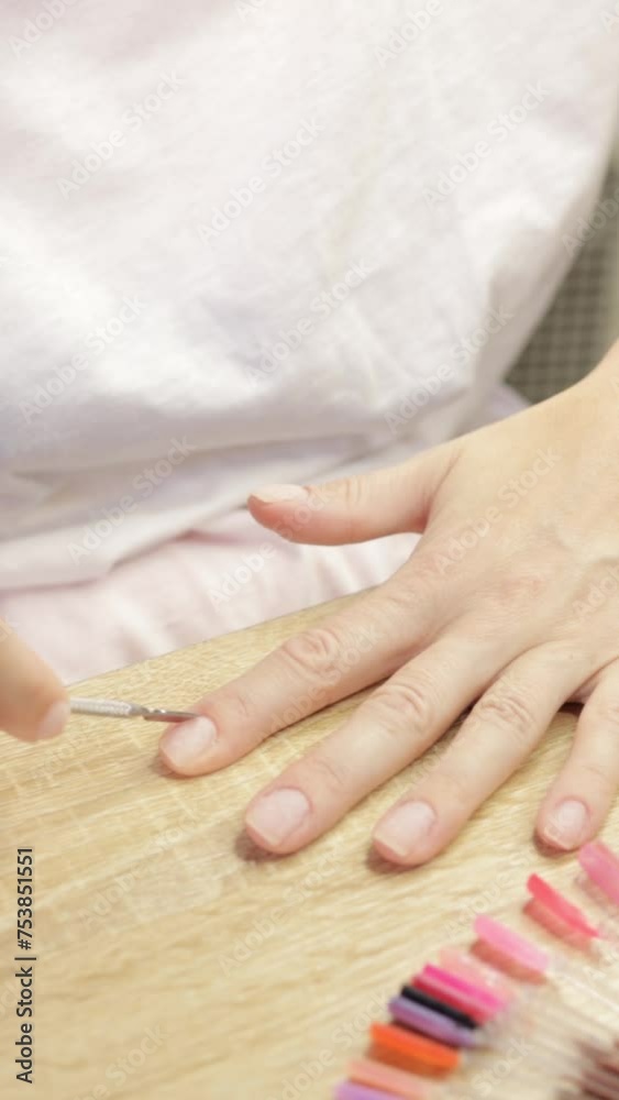 young woman is giving herself manicure at home, seated at table. She carefully trims and tidies her cuticles, display focus and precision in her grooming routine. Various nail care.Vertical young woman is giving herself manicure at home, seated at table. She carefully trims and tidies her cuticles, display focus and precision in her grooming routine. Various nail care.Vertical