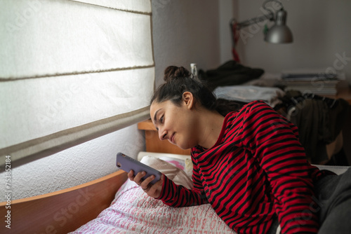 teenager lying in bed with her mobile phone