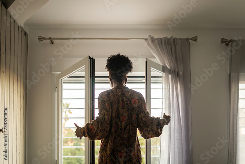 black woman at home looking out her bedroom window photo