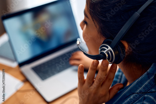 Close up of woman talking via headset while having online business meeting.