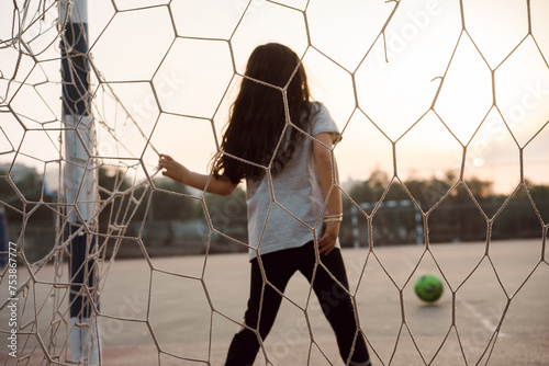 Young Girl Soccer Goalkeeper Defends Football Goal at Sunset. photo