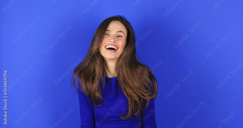 Woman look at camera see you, wave her hand, come to me. Hello, come to me! Portrait of friendly sociable woman in stylish blue top gesturing hi, welcoming with raised hand stand on blue background.