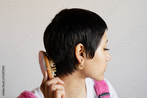 Haircare Concept. Young woman with combing her beautiful brown hair