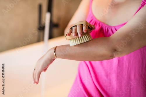 Closeup asian lady hold massage brush apply scrub arm photo