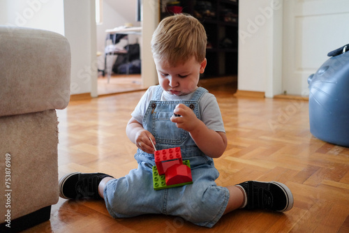 One year old boy sitting on the floor and playing with toys photo