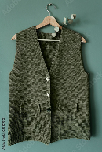 Knitted green vest on hanger. photo