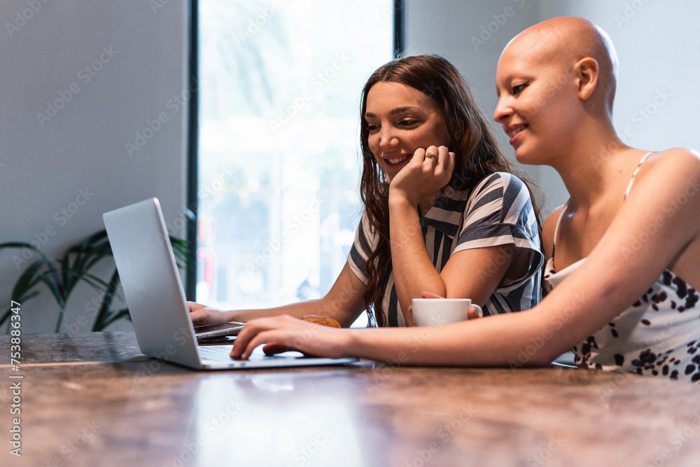 Joyful young ladies browsing laptop while having coffee break to Joyful young ladies browsing laptop while having coffee break to