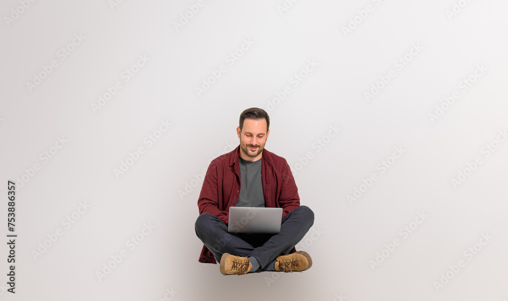 Focused handsome entrepreneur checking e-mail over laptop while sitting on isolated white background Focused handsome entrepreneur checking e-mail over laptop while sitting on isolated white background