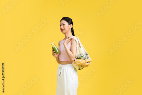 young woman carries fresh vegetables in string mesh bag photo