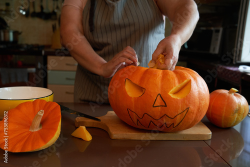 Carving: Woman Working On Face Of Jack-O-Lantern photo