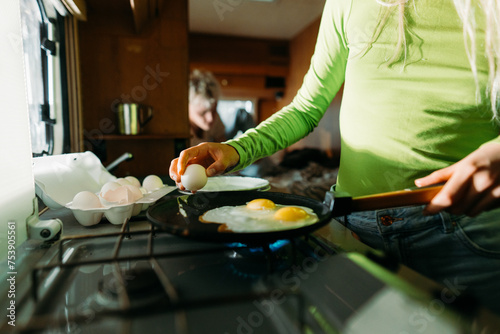 Woman frying eggs in van kitchen photo