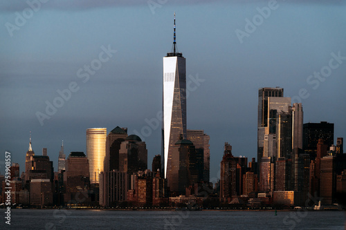 Contemporary skyscrapers near calm river in sunlight