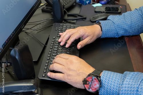 Masculine hands entering keystrokes on the keyboard for statistical data analysis.