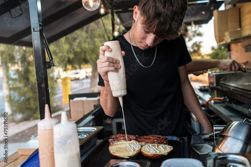 Chef Applying Sauce to Burger in Food Truck photo