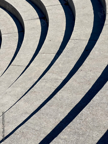 Rounded amphitheater seats in midday sun, create a fun shape photo