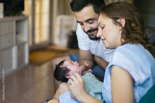 Parents lovingly caressing their newborn baby at home photo