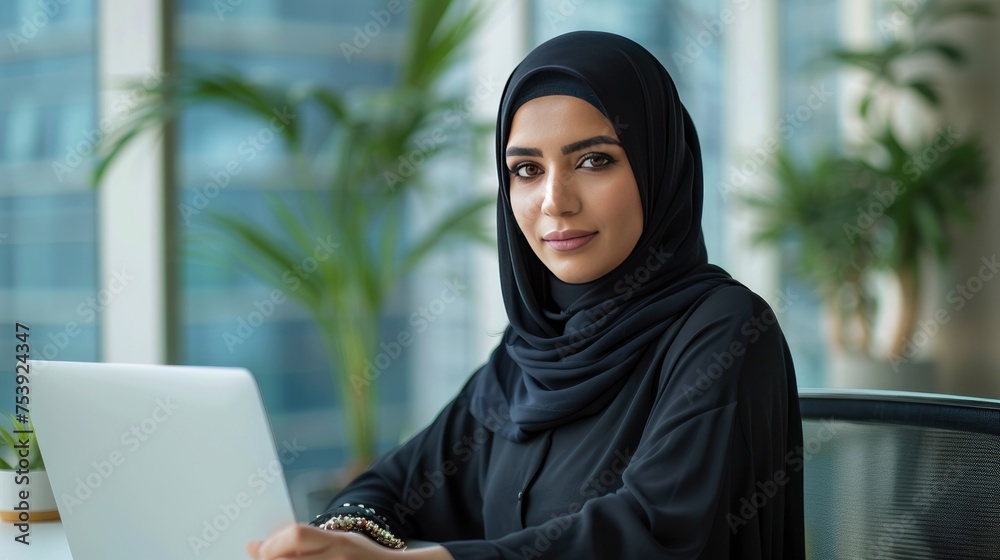 A Professional Middle Eastern Woman Executive. Wearing a Hijab. Working on a Laptop in a Corporate Office