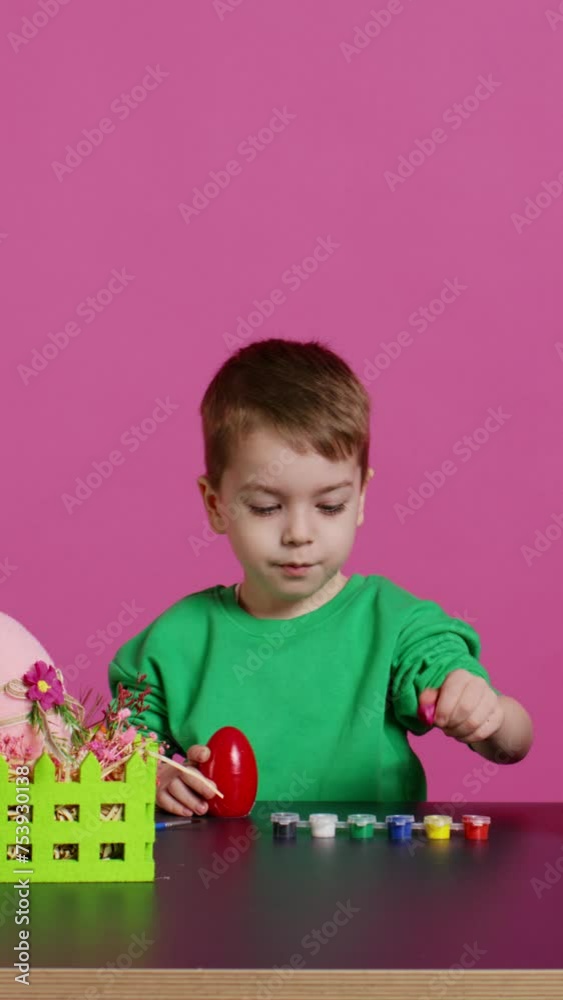 Small sweet child decorating eggs with stamps and watercolor, preparation for easter sunday holiday. Joyful little boy having fun coloring festive decorations, painting designs in studio. Camera B. Small sweet child decorating eggs with stamps and watercolor, preparation for easter sunday holiday. Joyful little boy having fun coloring festive decorations, painting designs in studio. Camera B.