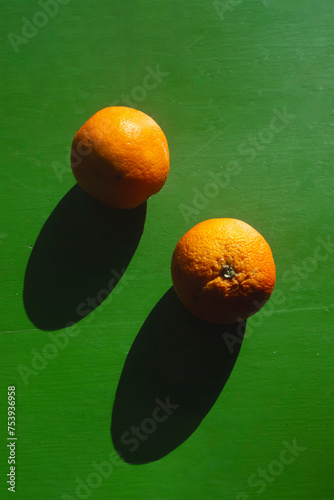 Juicy oranges ona green wooden table with direct sunlight photo