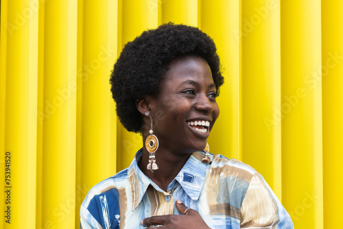 Cheerful stylish black woman standing on colorful yellow wall photo