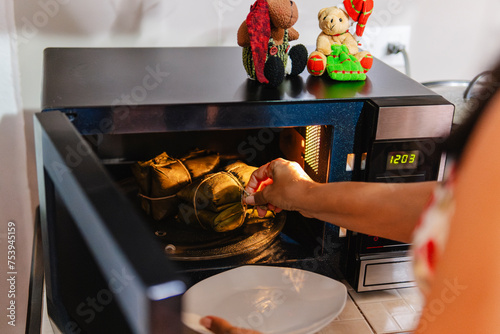 Woman heating tamales in microwave. photo