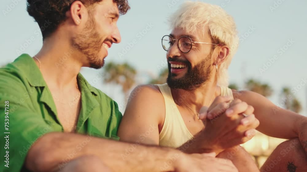 Close up, young gay couple crossing their arms while sitting on the beach