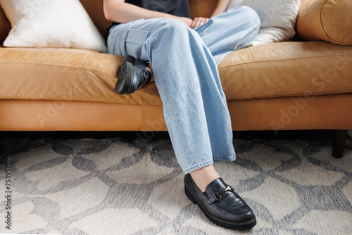 Person in jeans sits on leather couch photo