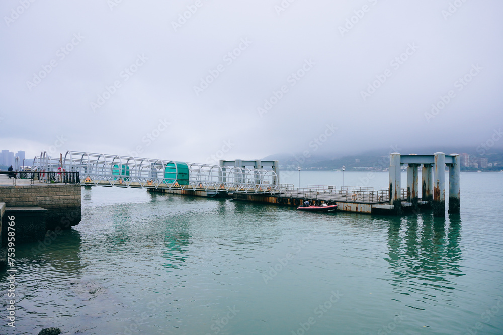 Bali, New Taipei, Taiwan, Republic of China, 01 22 2024: Cruise ferry boat and port on Clean Tamsui river in a raining day in winter	
