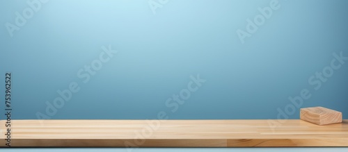 A wooden block of wood is placed on top of a wooden table. The table is set against a plain blue background, creating a simple and minimalist composition.