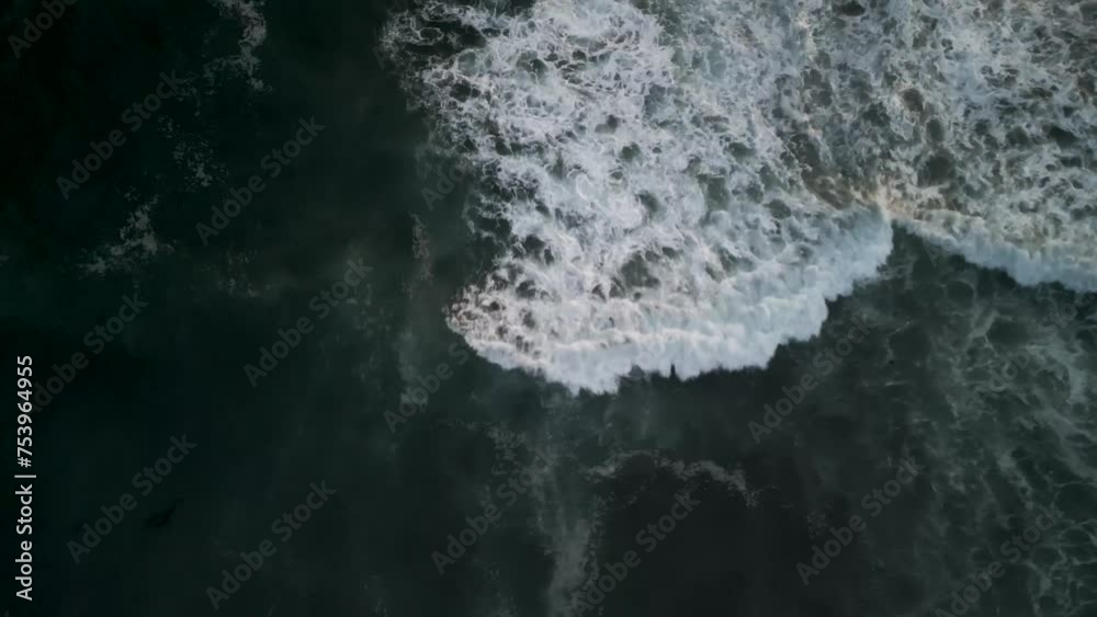Drone bird's eye view over the deep blue ocean waves and beach. Beautiful waves roll onto the sandy shore at sunset. Water texture, 4K Drone bird's eye view over the deep blue ocean waves and beach. Beautiful waves roll onto the sandy shore at sunset. Water texture, 4K