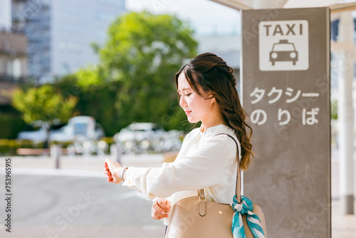 タクシー乗り場でタクシーを待つビジネスウーマン（遅い・遅刻・イライラ） 