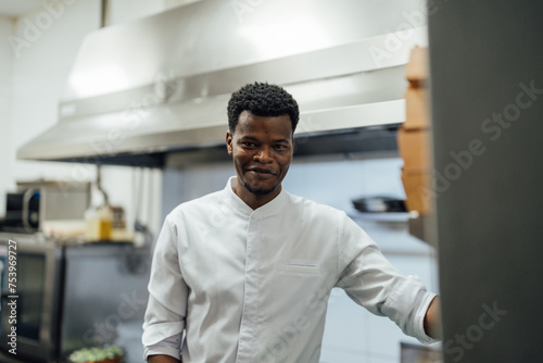 Happy black man in uniform standing in kitchen photo