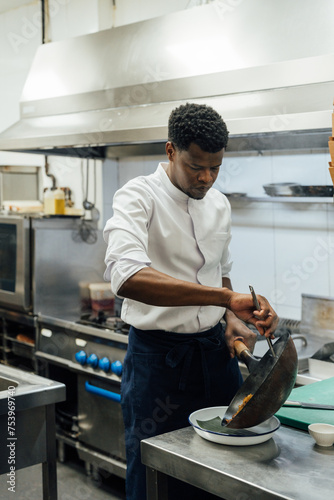Black chef putting wok on plate