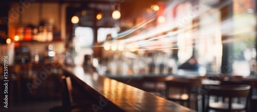 A defocused interior shot of a bustling restaurant bar, featuring blurred lights, people socializing, and drinks being served.