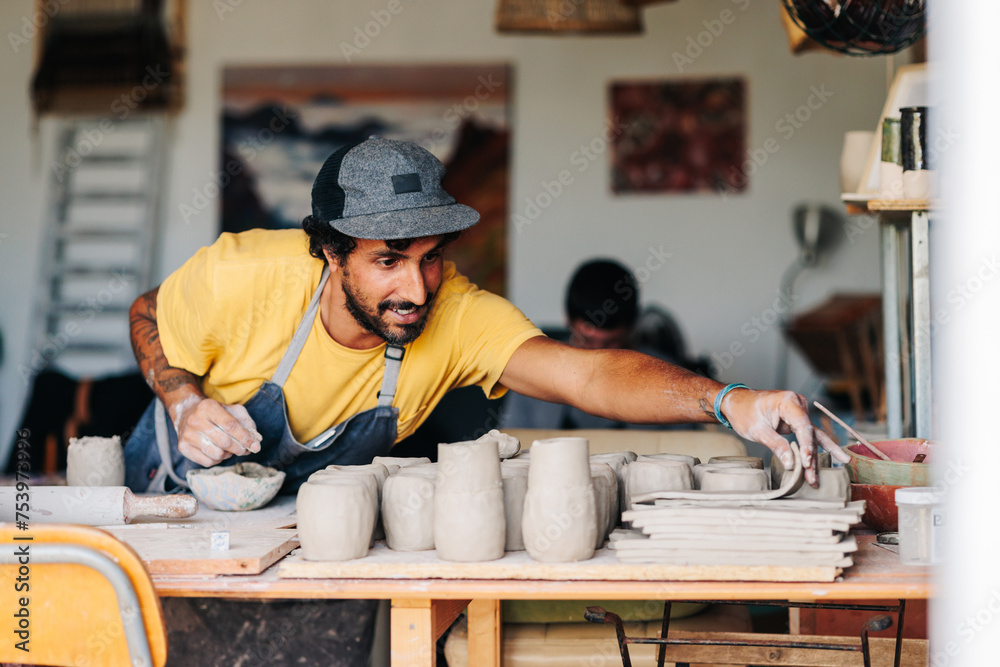 Potter working in his ceramic studio making clay pieces Potter working in his ceramic studio making clay pieces