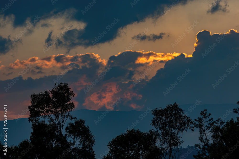 Fototapeta premium Beautiful afterglow over the eastern Andes mountains of central Colombia, with a pretty cloudy sky and some trees below.