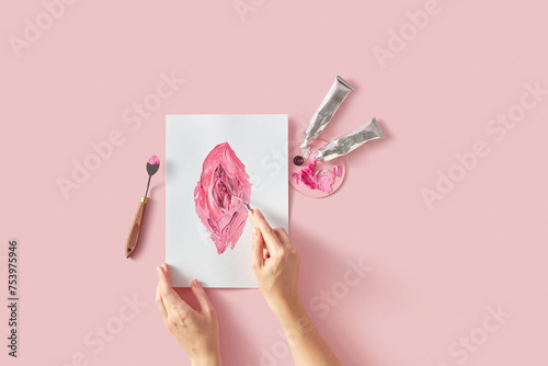 Female artist painting abstract vagina on canvas with spatula photo