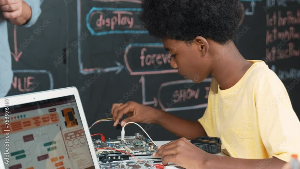 Boy Learning Tech Cute african boy learning to use electronic tool while laptop display ...