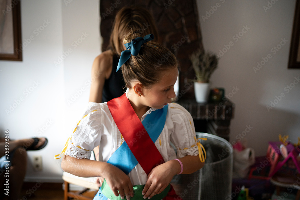 Unrecognizable woman dressing young daughter Unrecognizable woman dressing young daughter