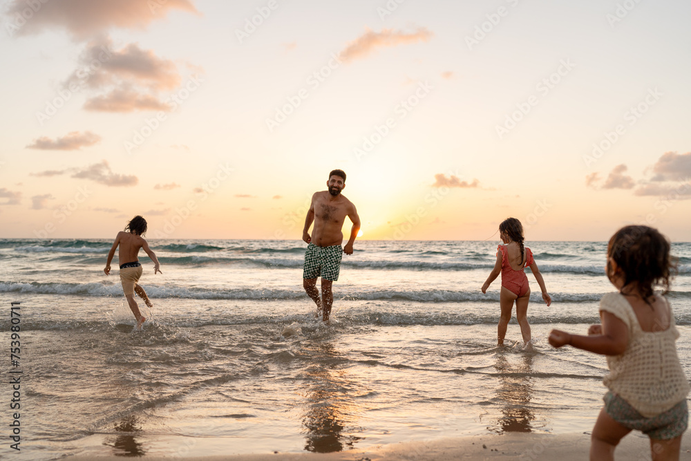 Sibling playing in the water with dad on an empty beach. Sibling playing in the water with dad on an empty beach.