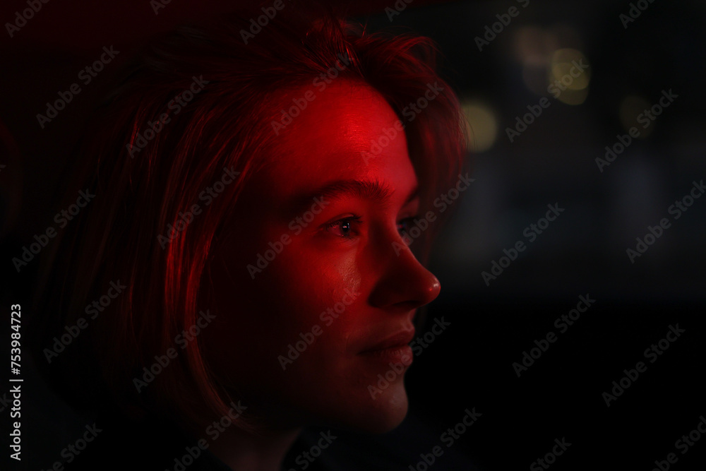 Red light reflecting on blond girl face: low light profile portrait Red light reflecting on blond girl face: low light profile portrait