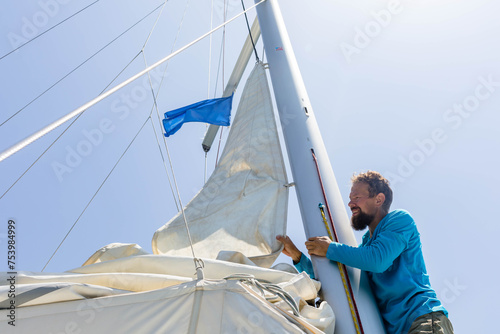 Sailor folds mainsail photo