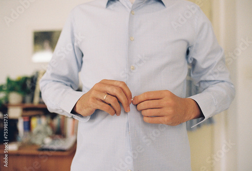 A man buttoning up his shirt. photo