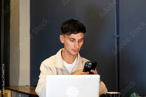 young man looks at his cell phone on his day of homme oficce photo