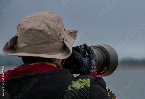 Fotógrafo en acción en el mar con un teleobjetivo y un gorro