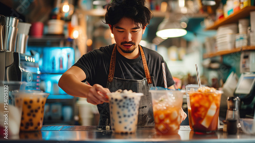 Man behind the counter of a boba tea shop making tapioca pearl milk teas.
