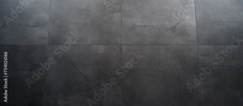 A black and white image showing a person standing on a decorative dark grey concrete floor, holding a cell phone in their hand.