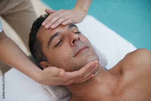 Hotel  spa and man relax for facial massage on table in resort  calm and care for body in vacation. Holiday  luxury and male person on break for weekend and lodge with treatment for skincare