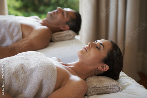 Luxury, massage and couple relax in spa for care of body with rest on bed of retreat for honeymoon. Hotel, man and woman together in resort for health, wellness and holiday for skincare in break photo